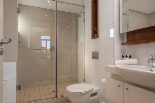 a bathroom with a shower and a toilet and a sink at Suite 515, Zimbali Suites in Ballito