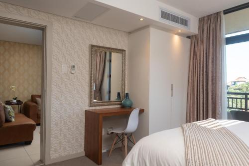 a bedroom with a bed and a mirror and a chair at Suite 515, Zimbali Suites in Ballito