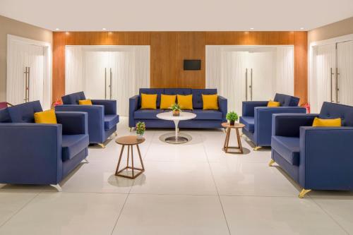 a living room with blue couches and yellow pillows at Novotel Jeddah Tahlia in Jeddah