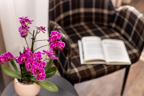 a table with a vase of flowers and an open book at Arcus Hotel München Messe in Feldkirchen