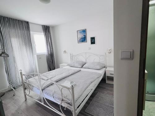 Apartman Castle في Tušilović: غرفة نوم بيضاء مع سرير أبيض ونافذة