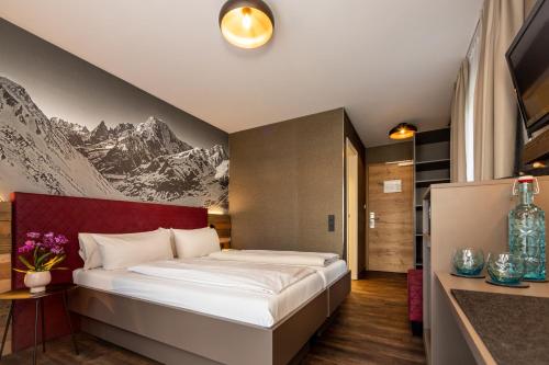 a bedroom with a bed with a mountain mural on the wall at Arcus Hotel München Messe in Feldkirchen