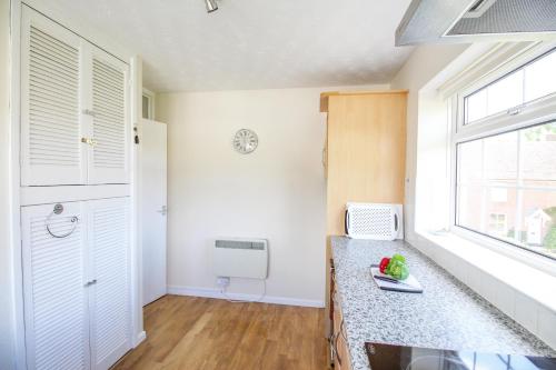 cocina con paredes blancas, ventana y encimera en West Lulworth Apartment, en Wareham
