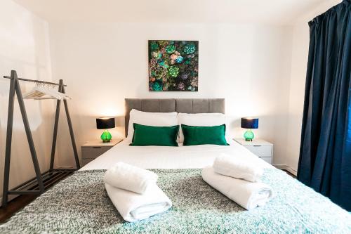 sypialnia z dużym łóżkiem z 2 zielonymi poduszkami w obiekcie Beech Road Apartment St Albans by PAY AS U STAY w Saint Albans