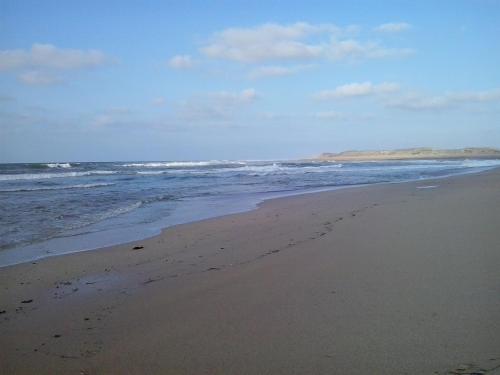 a sandy beach with waves in the ocean at Appartement Bella Vista in Bouznika