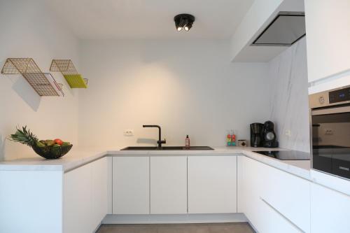 eine weiße Küche mit weißen Schränken und einem Waschbecken in der Unterkunft Villa Feliz in Nieuwpoort