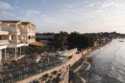 a hotel with tables and chairs next to the water at Panorama Inn in Lithakia