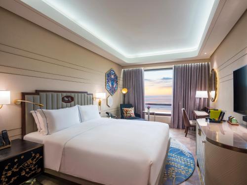 a hotel room with a large white bed and a desk at Admiral Hotel Manila - MGallery Collection in Manila