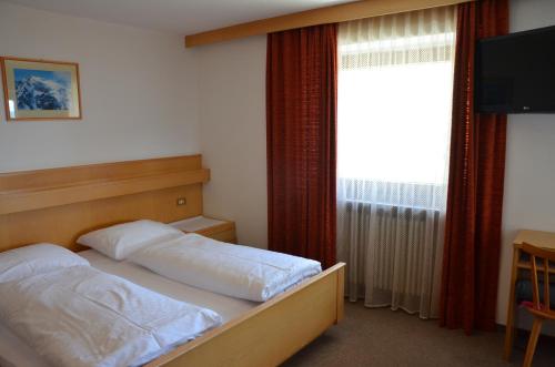 a bedroom with a bed and a television and a window at Pension Schifferegger in Maranza
