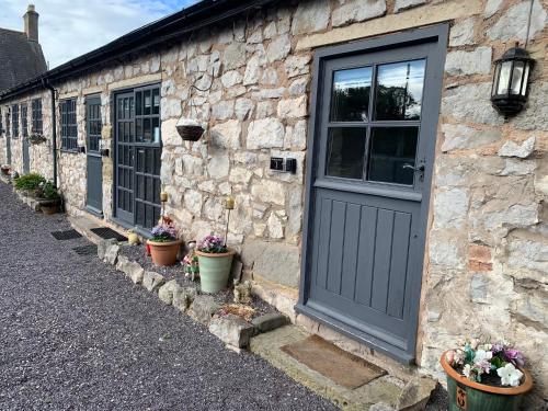 un edificio de piedra con una puerta y algunas macetas en Dwylig Isa Holiday Cottages, en Rhuddlan