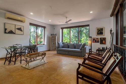 a living room with a couch and a table and chairs at Saffronstays Casa Del Palms, Alibaug - luxury pool villa with chic interiors, alfresco dining and island bar in Alibaug