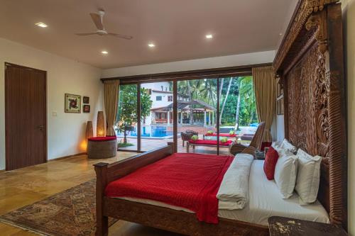 a bedroom with a large bed with a red blanket at Saffronstays Casa Del Palms, Alibaug - luxury pool villa with chic interiors, alfresco dining and island bar in Alibaug