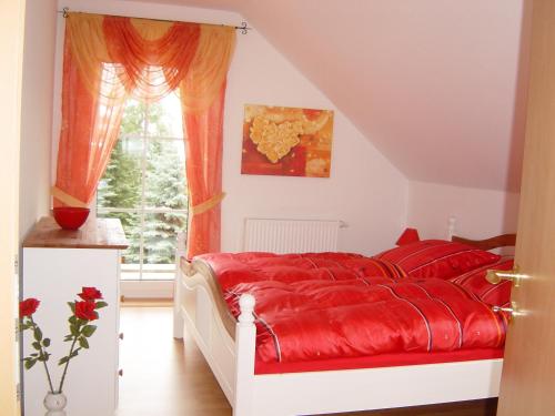 a bedroom with a red bed and a window at Ferienhaus Vogtlandresidenz in Auerbach