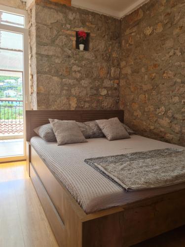 Bett in einem Zimmer mit einer Steinmauer in der Unterkunft Dream House Rajic in Trpanj