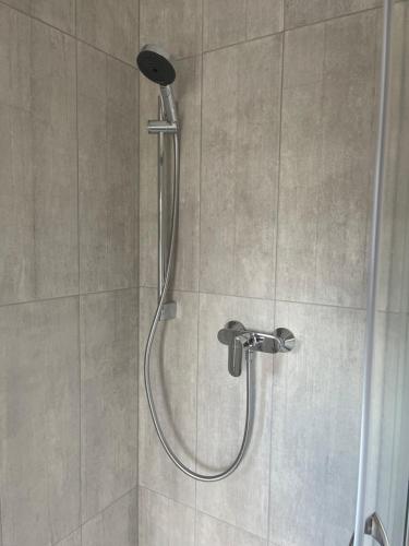a shower with a shower head in a bathroom at Laukbaloži Holiday houses in Jūrkalne