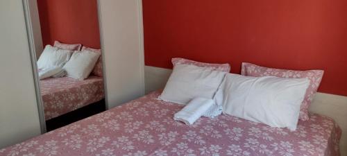 a bedroom with a bed with white pillows and a mirror at Cantinho dos Rehm in Fortaleza