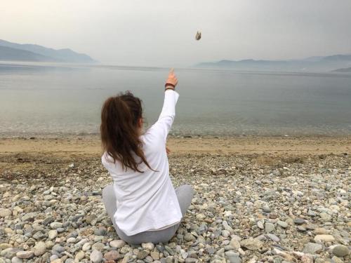 a woman sitting on the beach flying a kite at North Evia Evanthia Greece in Kourkouloí