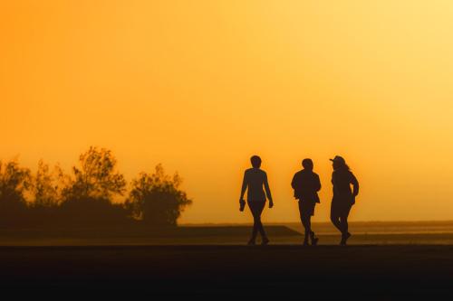 three people walking in a field at sunset at Flamingo Villas Boutique Hotel in Walvis Bay