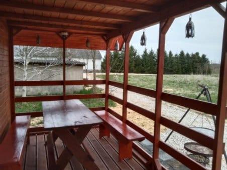 a wooden porch with a bench on a wooden deck at domek letniskowy Agroturystyka Sajkiewicz in Chmielnik