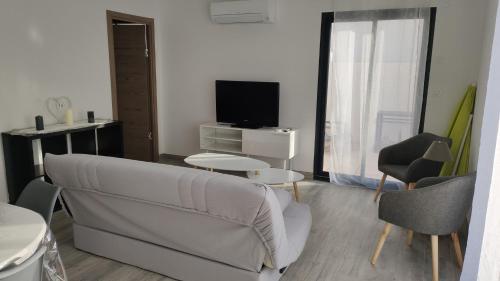 a living room with a couch and a tv at Jolie petite maison à 50 mètres de la plage in Cap d'Agde