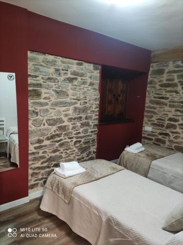 two beds in a room with a stone wall at Casa marina in Puebla de Sanabria