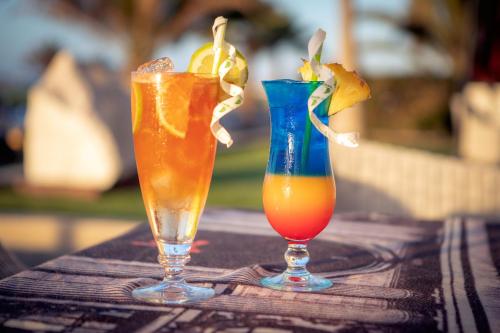 two cocktails sitting on a wooden table with a vase at Flamingo Villas Boutique Hotel in Walvis Bay