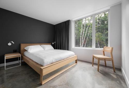 a bedroom with a bed and a chair and a window at Luxurious Chalet with Pool, Sauna, Spa & Amazing View in La Malbaie