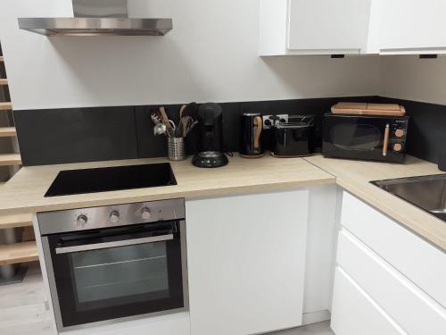 a kitchen counter with a stove and a microwave at Manoir de l'As de Trèfle in Isneauville