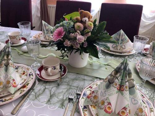 a table with plates and a vase of flowers on it at Hotel Eulenhof in Gransdorf