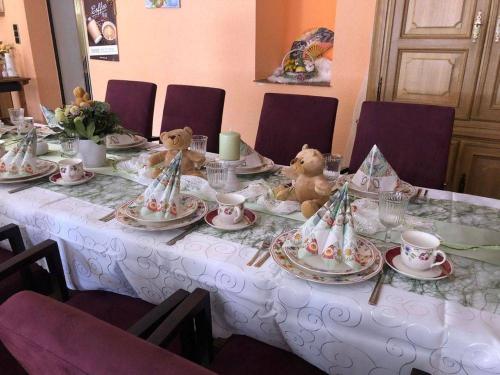 deux ours en peluche assis à une table avec des assiettes et des tasses dans l'établissement Hotel Eulenhof, à Gransdorf