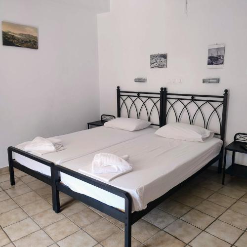 a black bed with white sheets and pillows on it at Maroudas Stavros Apartments in Vathi, Ithaka
