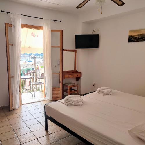 a bedroom with two beds and a view of a balcony at Maroudas Stavros Apartments in Vathi, Ithaka