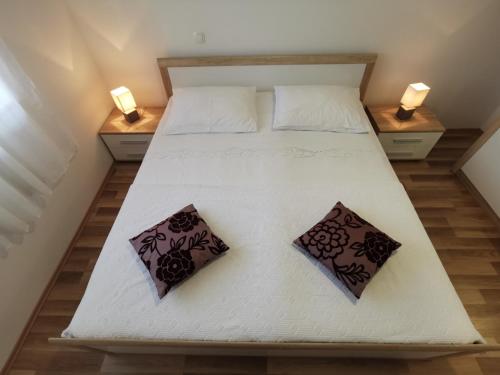a large white bed with two pillows on it at Apartmani Peco Duće in Duće