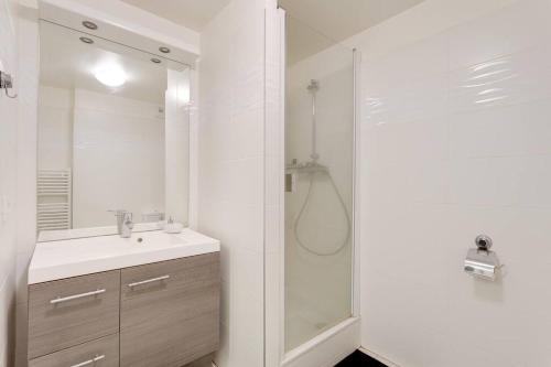 een witte badkamer met een douche en een wastafel bij Appartement de Standing Aux Portes de Paris in Nogent-sur-Marne