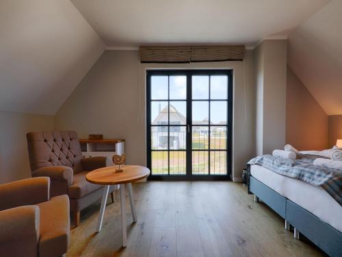a bedroom with a bed and a table and a chair at Reetland am Meer - Premium Reetdachvilla mit 3 Schlafzimmern, Sauna und Kamin F19 in Dranske