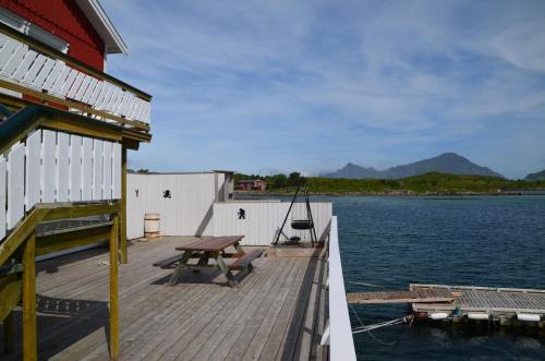 a wooden dock with a picnic table on the water at Lydersen Rorbuer Budget Hostel & Private Apartments in Fredvang