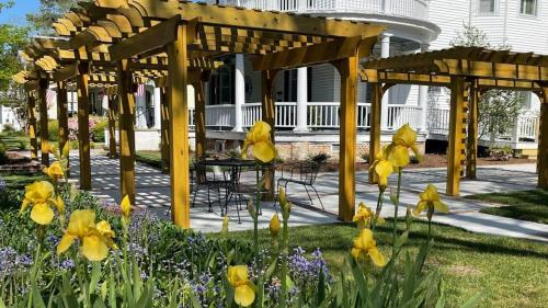 a wooden pergola in front of a house with flowers at The Edenton Collection-Captain's Quarters Inn in Edenton