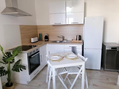 - une petite cuisine blanche avec une table et des chaises blanches dans l'établissement Le manut, charme et confort, à Dijon