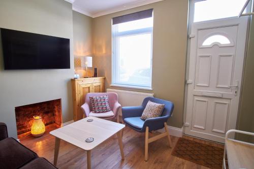 a living room with two chairs and a fireplace at NEW 2BD Victorian Terraced House Loughborough in Loughborough
