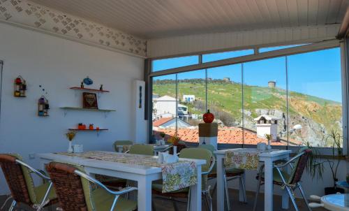 una sala da pranzo con tavoli e sedie e una grande finestra di Bozcaada e2 Deniz Otel a Bozcaada