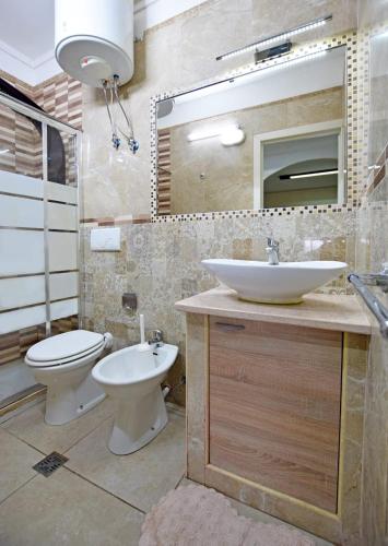 a bathroom with a sink and a toilet and a mirror at Les Suites Corso Roma in Gallipoli