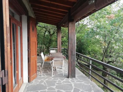 um alpendre de uma casa com uma mesa e cadeiras em La casetta nel bosco em Salò