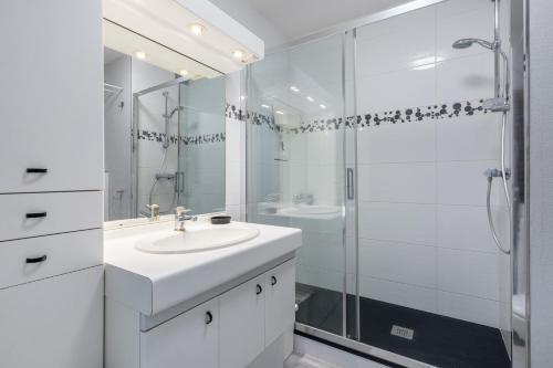 une salle de bain blanche avec un lavabo et une douche dans l'établissement Le Proust, à Cabourg