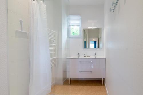 uma casa de banho branca com um lavatório e um espelho em Les Bleuets em Pléneuf-Val-André