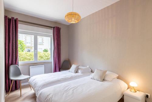 two beds in a room with a window at Les Bleuets - Duplex avec vue mer in Pléneuf-Val-André