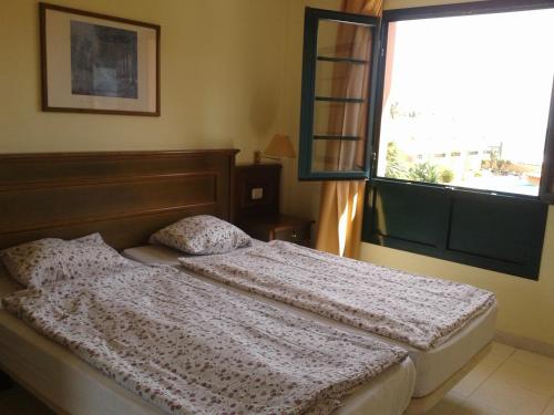 een slaapkamer met een bed en een groot raam bij Gepflegte Apartment-Anlage mit Pool und Garten in La Playa Calera