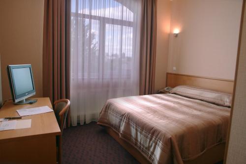 a hotel room with a bed and a desk with a computer at Victoria Hotel in Kharkiv