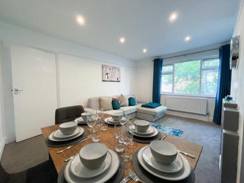 ein Wohnzimmer mit einem Tisch mit Tellern und Weingläsern in der Unterkunft Central Chelmsford Apartment with Garden in Chelmsford
