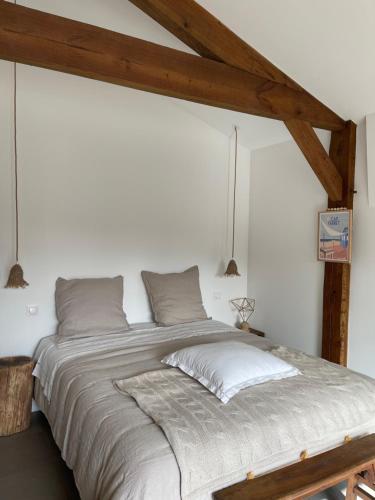 a large bed in a white room with wooden beams at OSTAL 158 in Le Barp