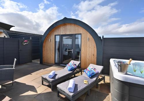 an outdoor patio with a wooden building with two couches at 2 Sinclair bay lodges in Keiss